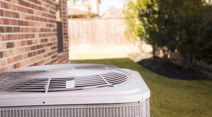 Modern air conditioning unit on concrete in a residential backyard by Aptus Home Services.