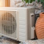 Outdoor heat pump unit beside a decorative clay pot, illustrating HVAC installation and energy efficiency solutions relevant to Aptus Home Services.